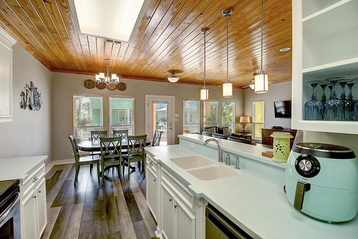 Your open-concept kitchen flows into the dining space, where wood ceilings and modern appliances create the perfect setting for memorable meals together.