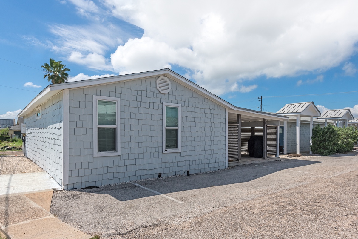 Modern rental cottage with coastal charm featuring clean gray shingles and plenty of parking space for a relaxing getaway.