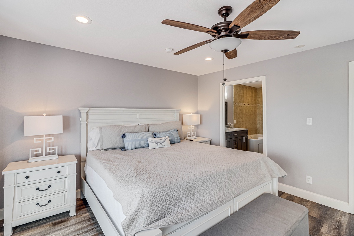 Your peaceful retreat awaits with soft gray walls, crisp white bedding, and a gentle ceiling fan to keep you comfortable all night.