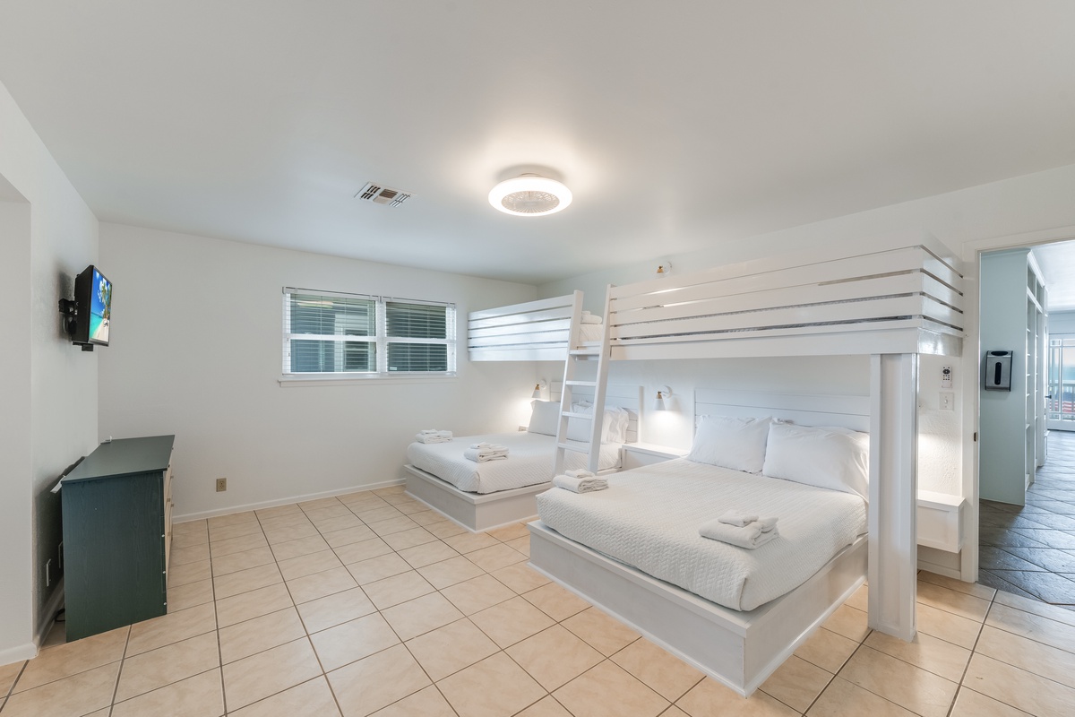 Unwind in your spacious bedroom featuring a unique bunk bed setup with crisp linens and modern amenities for a comfortable stay.