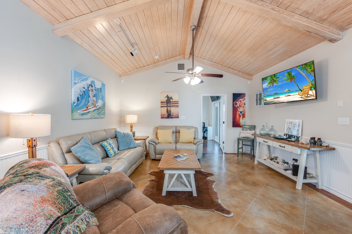 Relax under stunning vaulted wood ceilings in your spacious living room, complete with plush seating and coastal artwork.