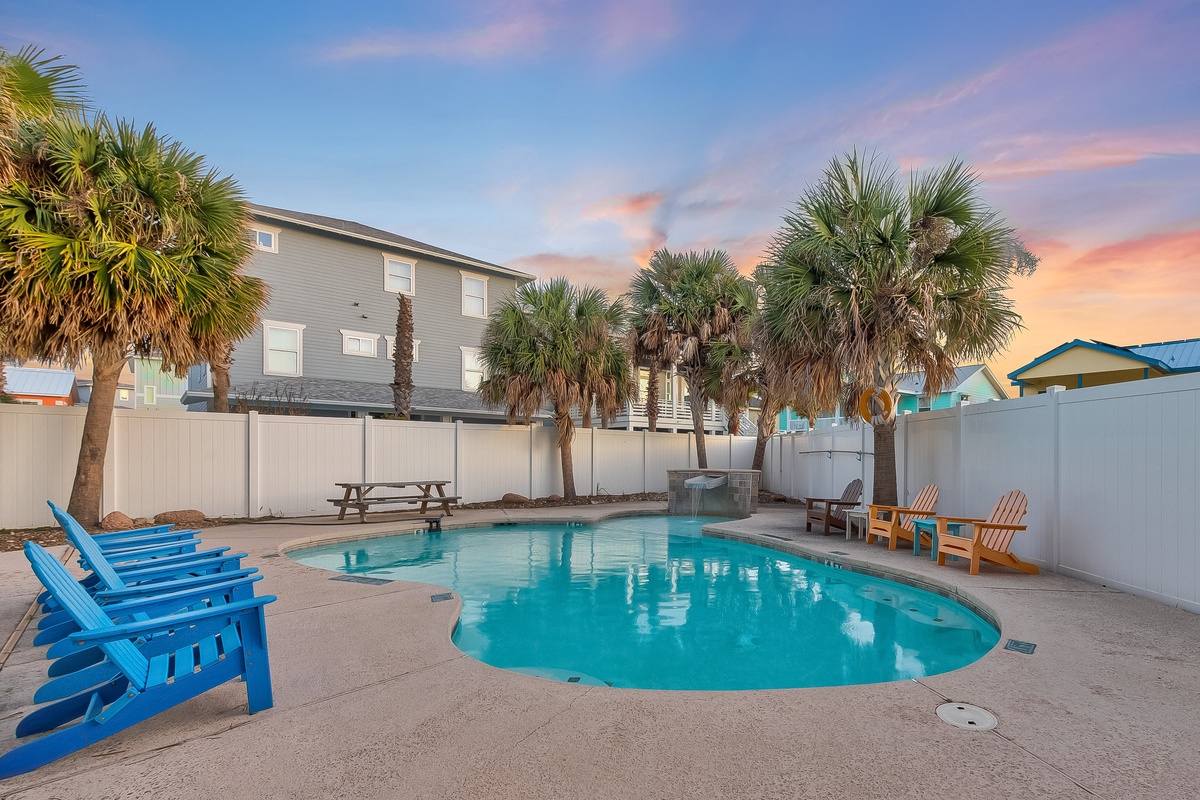 Private pool oasis surrounded by tropical palms and colorful Adirondack chairs, perfect for sunset swims and relaxation.