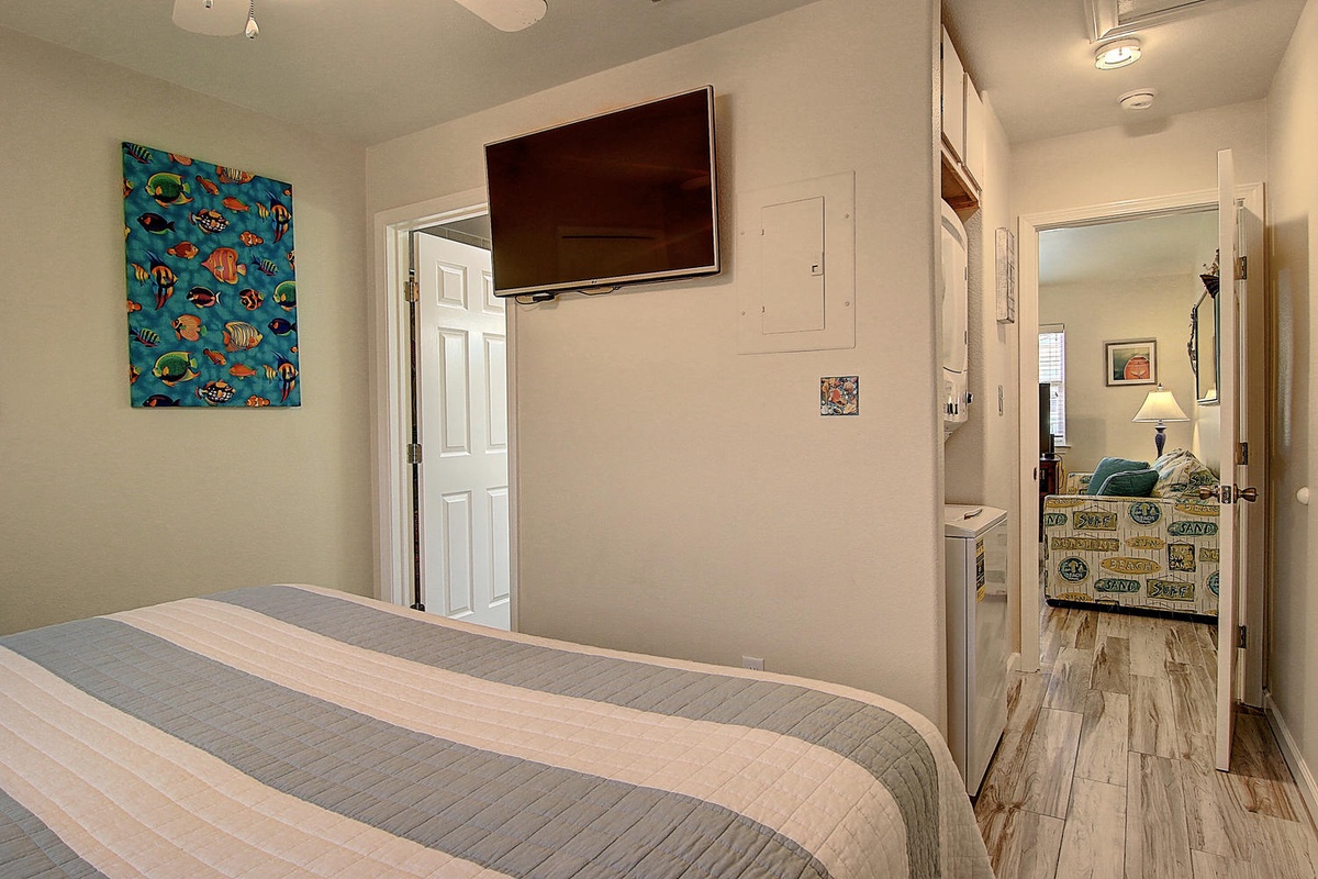Relax in your cozy bedroom with tropical artwork, flat-screen TV, and connecting ensuite for ultimate convenience.