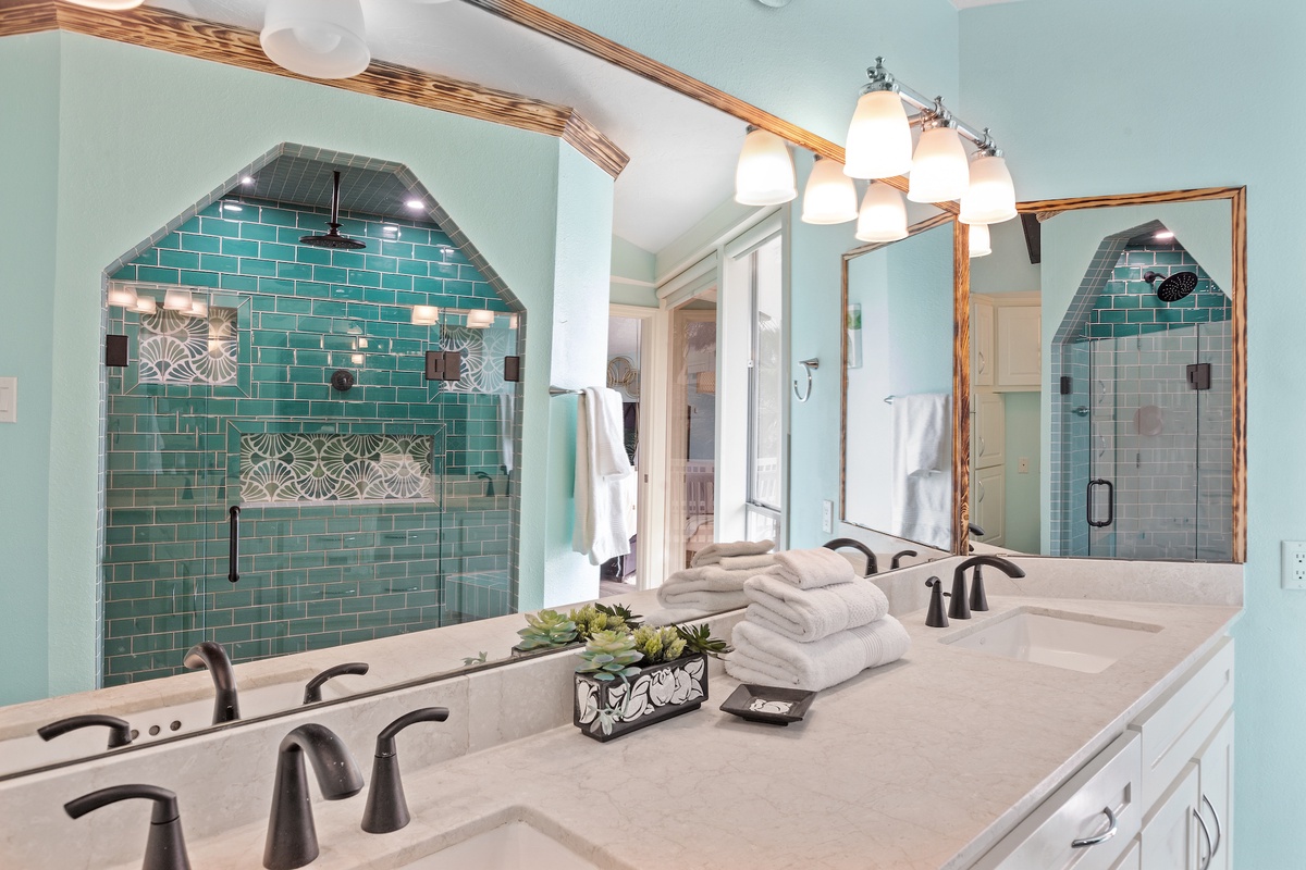 Your stunning master bathroom features elegant green tile work, dual vanities, and a luxurious tiled shower where you can unwind after exploring.