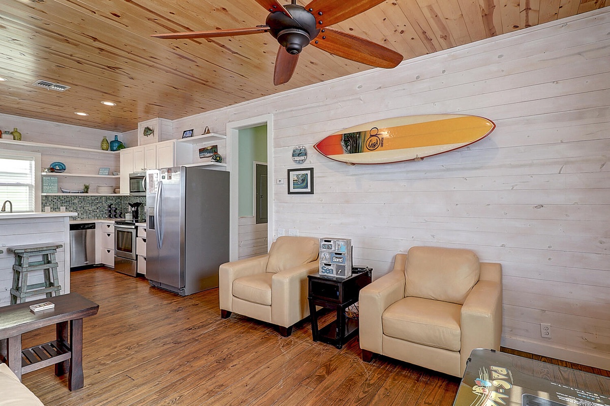 Relax in this coastal-inspired open living space where surfboard art and warm wood create your perfect beach retreat.