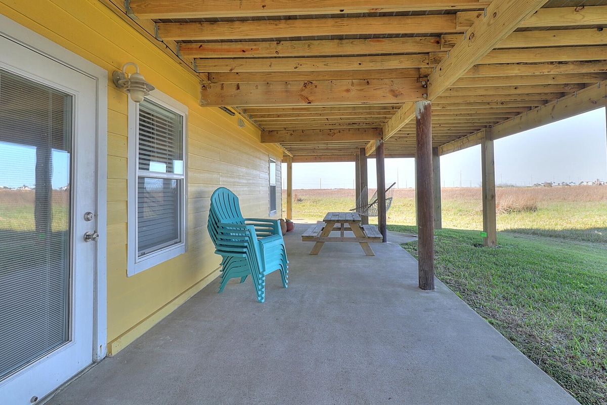 Unwind on your private covered patio with turquoise chairs and picnic table, surrounded by peaceful countryside views.