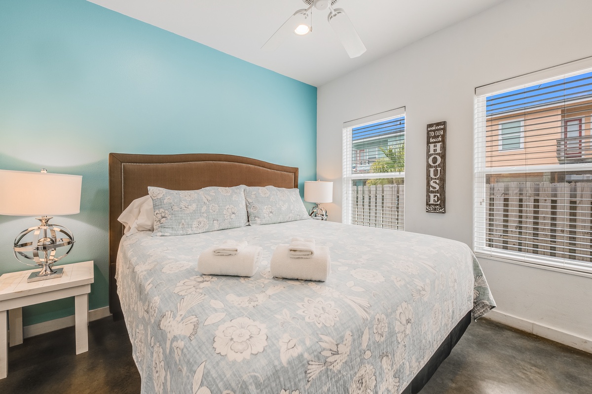 Unwind in this serene bedroom featuring a plush queen bed, calming turquoise accent wall, and thoughtful touches like fresh towels waiting for your arrival.