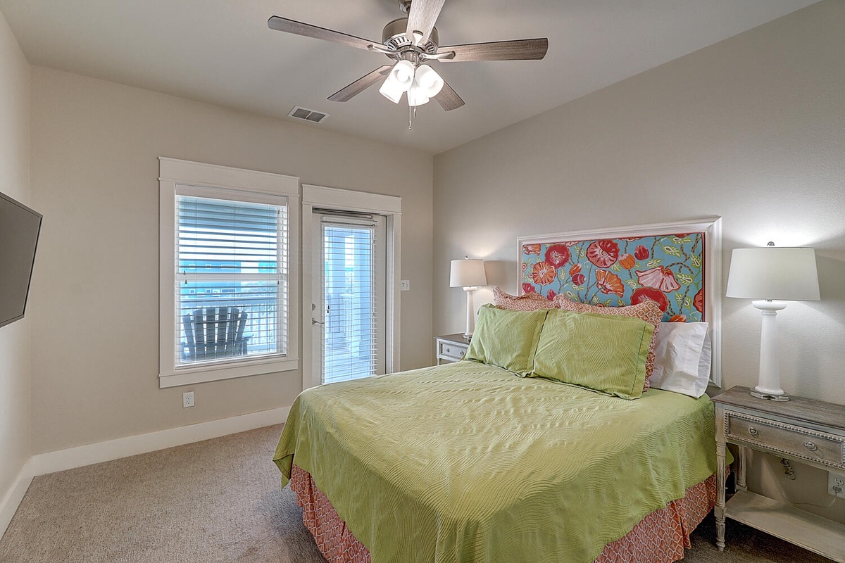 Unwind in this bright bedroom with cheerful tropical headboard and soft linens, where gentle ceiling fan keeps you comfortable.