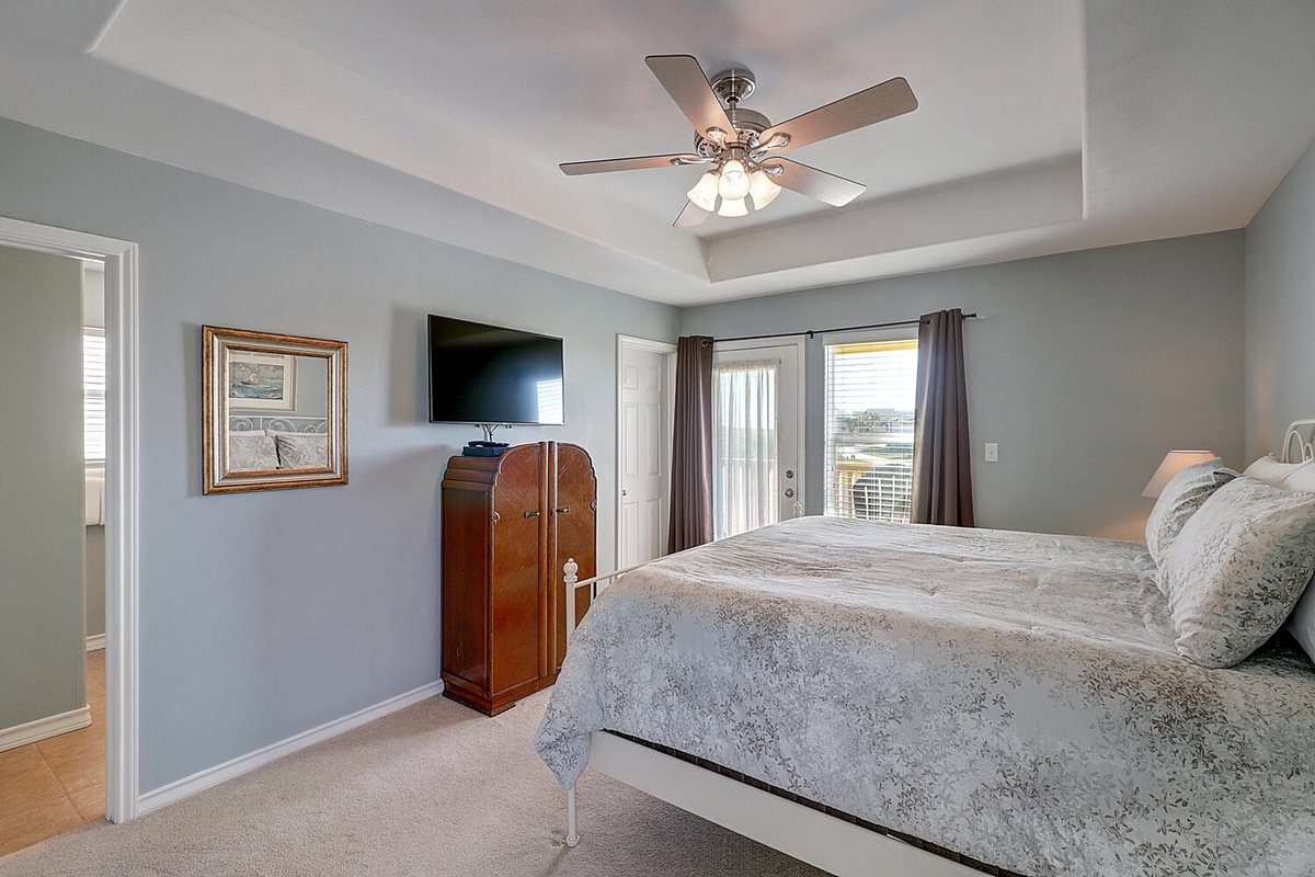 Relax in your peaceful bedroom with soft gray walls, vintage armoire, and gentle ceiling fan keeping you cool all night.