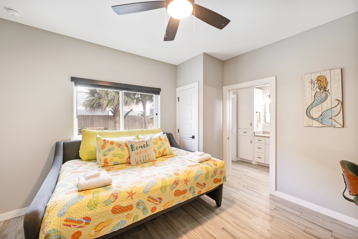 Relax in your cheerful bedroom with beach vibes, complete with cooling ceiling fan and peaceful garden views.