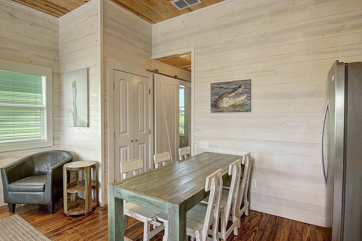 Your rustic dining space features a handcrafted farmhouse table surrounded by charming wooden chairs, perfect for sharing meals beneath warm exposed beams.
