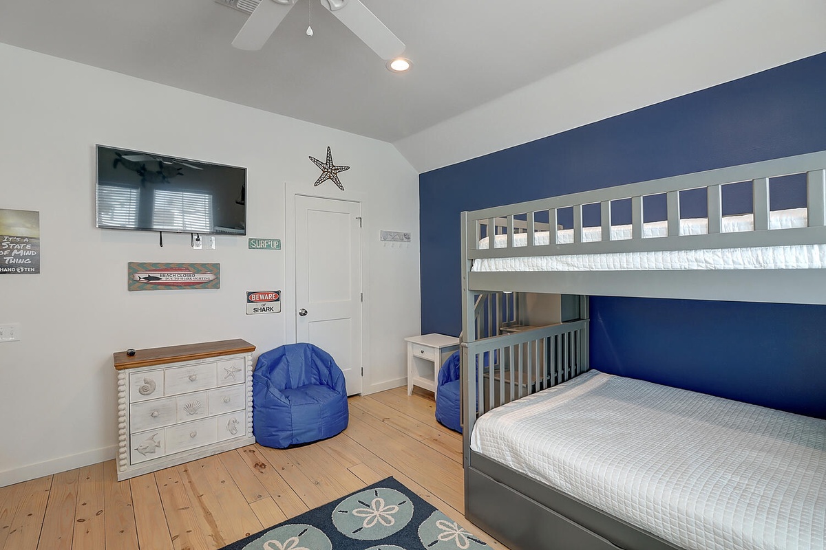 Your kids will love this coastal-themed bunk room with its nautical charm, cozy bean bag, and entertainment setup for magical vacation memories.