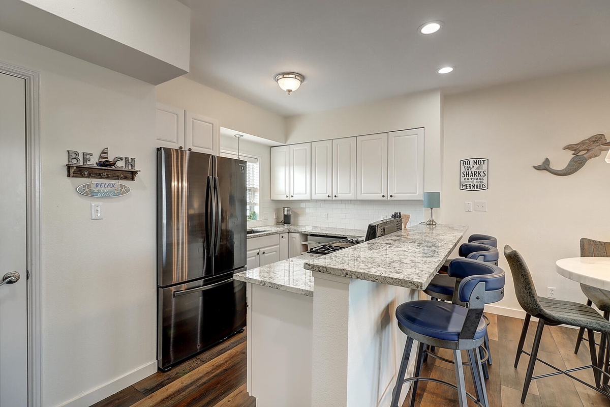 Your fully equipped kitchen awaits with granite counters, stainless appliances, and bar seating perfect for morning coffee or casual meals.