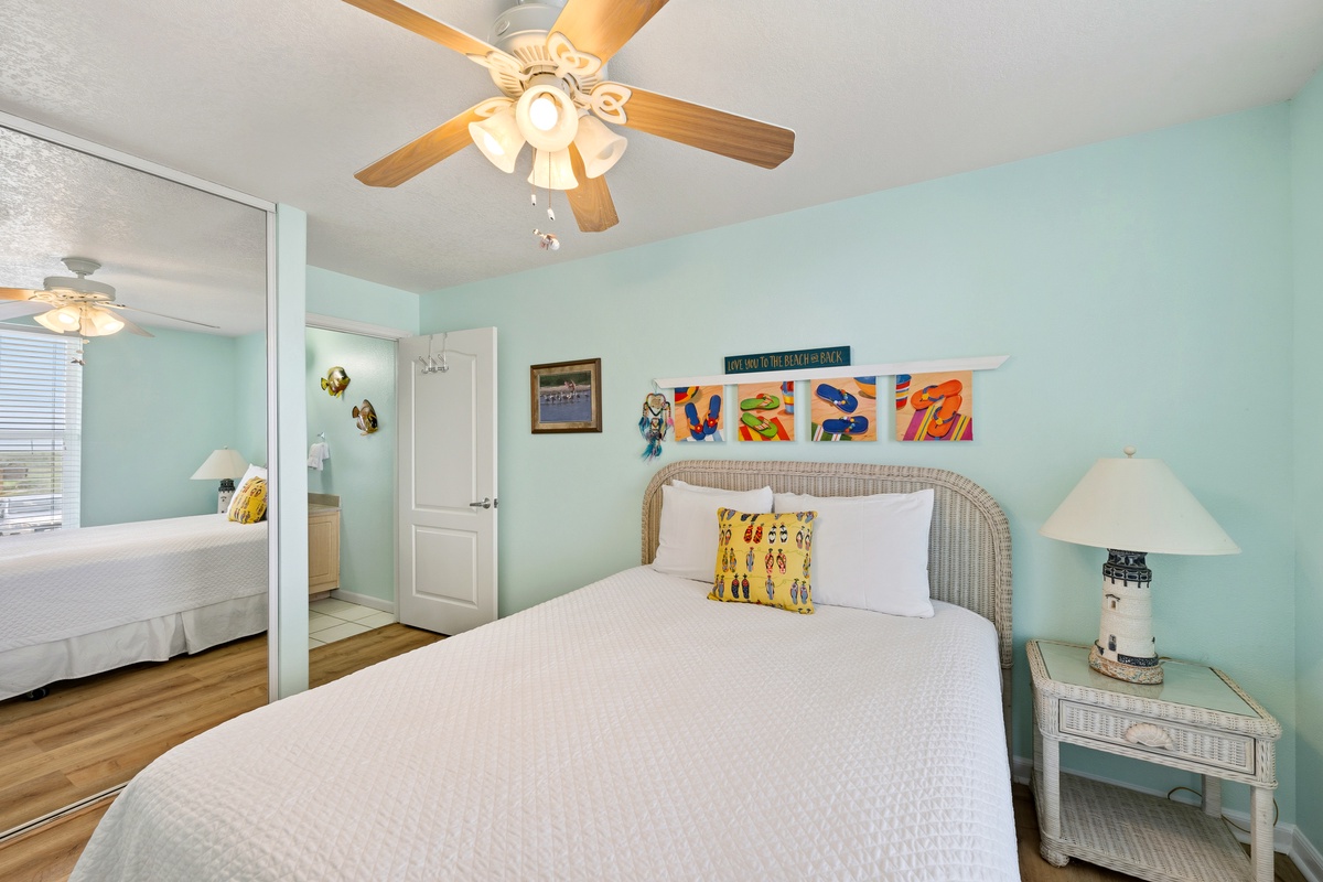 Unwind in your cheerful coastal bedroom, where soft aqua walls and vibrant artwork create a relaxing retreat. The wicker headboard and crisp linens invite you to settle in and dream of beach days ahead.
