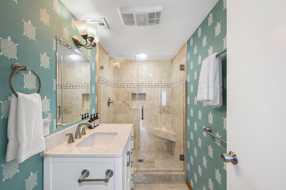 Step into your private sanctuary featuring a luxurious walk-in shower with dual showerheads, playful sea turtle wallpaper, and plush towels waiting for your arrival.