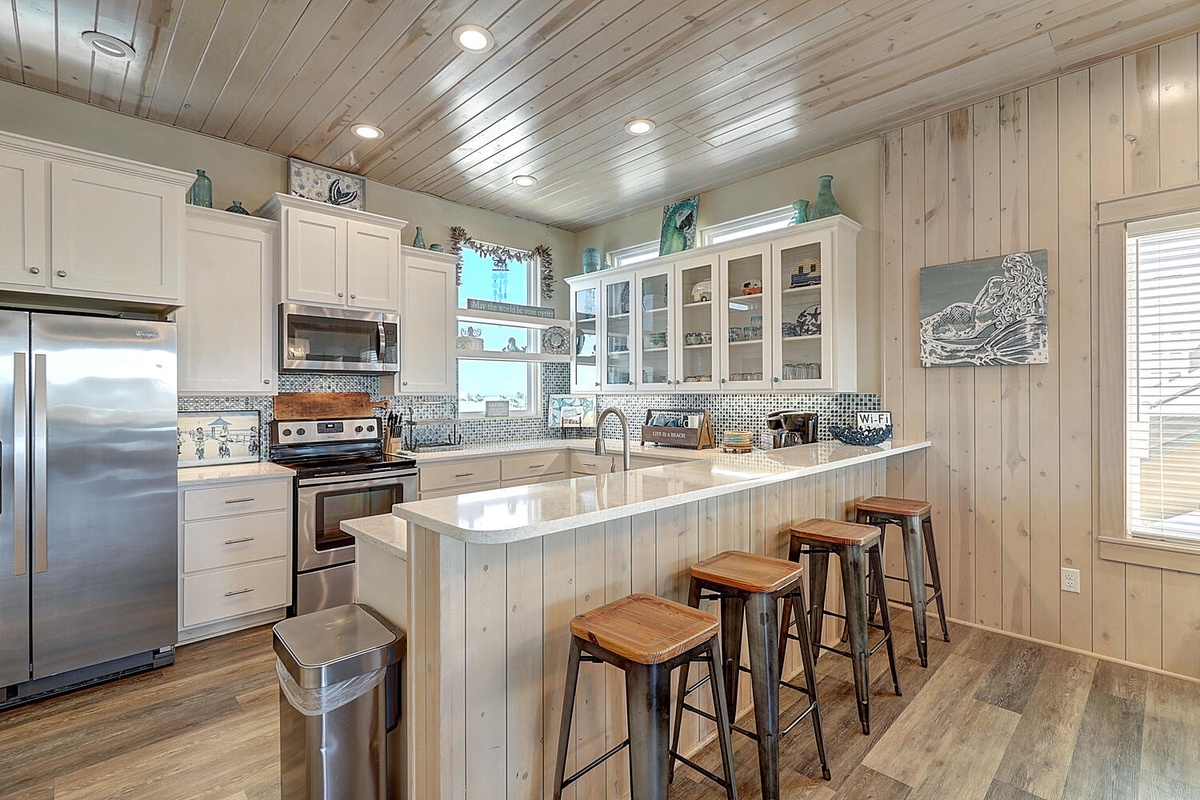 You'll love cooking in this bright coastal kitchen with gleaming counters, modern appliances, and charming breakfast bar seating for four.