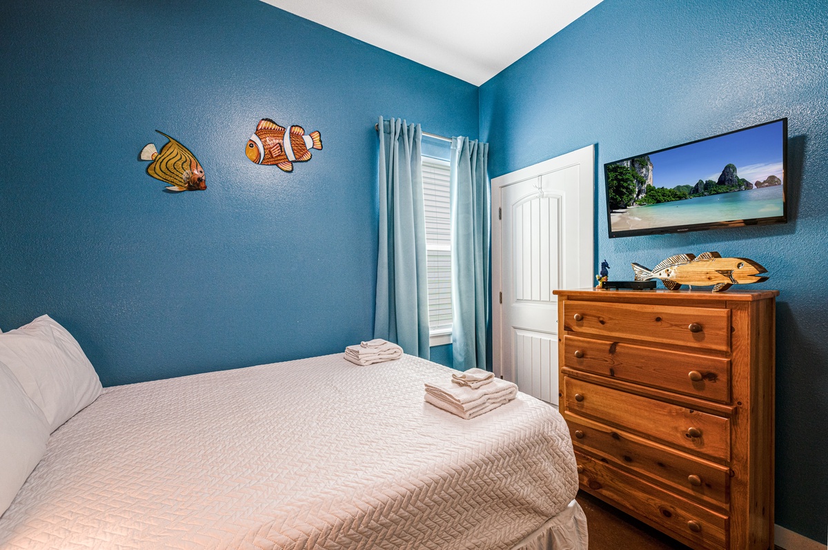 Dive into ocean dreams in your cozy bedroom with playful fish decor, warm wood furnishings, and crisp linens waiting for restful nights.