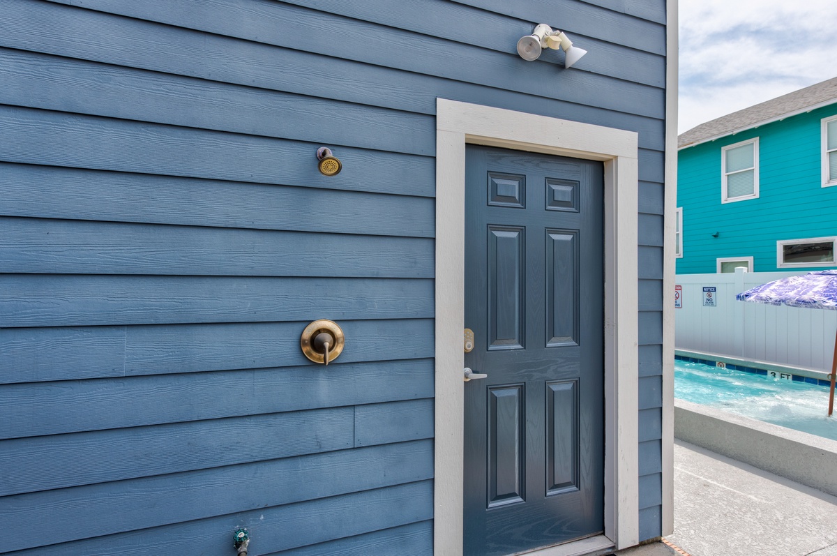 Bright blue building exterior with pool area visible nearby, showcasing the colorful coastal charm of this vacation property.