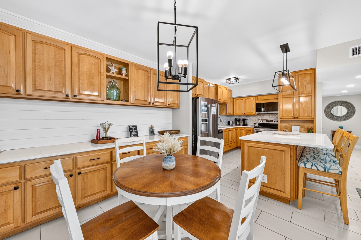 Spacious kitchen with warm wood cabinetry, modern lighting, center island, and cozy breakfast nook with built-in bench seating.