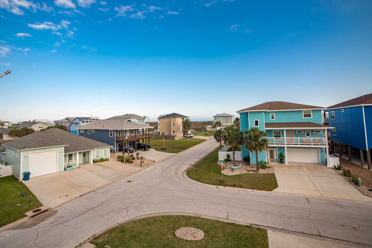 Colorful coastal neighborhood with well-maintained streets and tropical landscaping under clear blue skies.