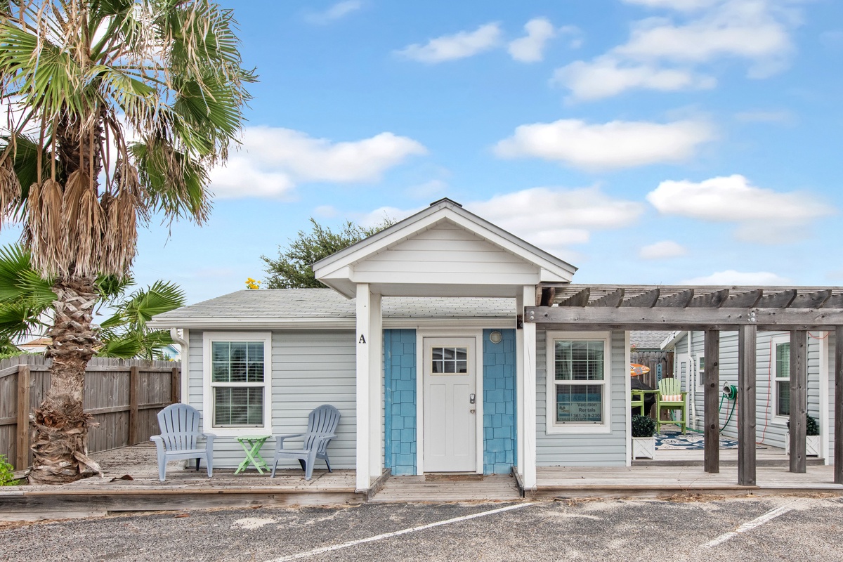 Charming coastal cottage with turquoise shutters and palm trees creates a perfect beach getaway retreat.