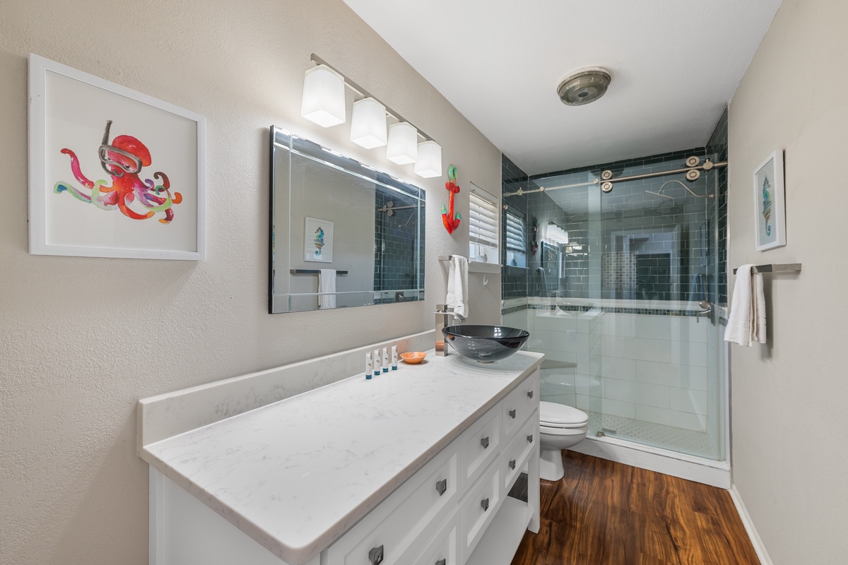 Step into your private spa-like retreat with a sleek walk-in shower, dual vessel sinks, and cheerful coastal touches that set a refreshing tone for your day.