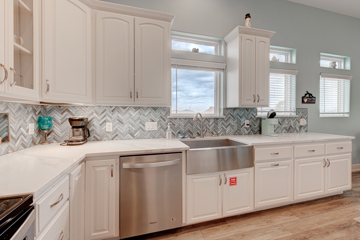Your spacious kitchen features white cabinetry, stainless steel appliances, and elegant chevron backsplash—perfect for preparing memorable meals.