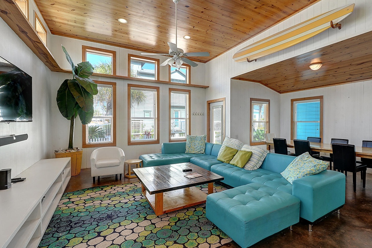 Sink into plush turquoise sectional seating where warm wood ceilings and abundant natural light create your perfect retreat for relaxation.