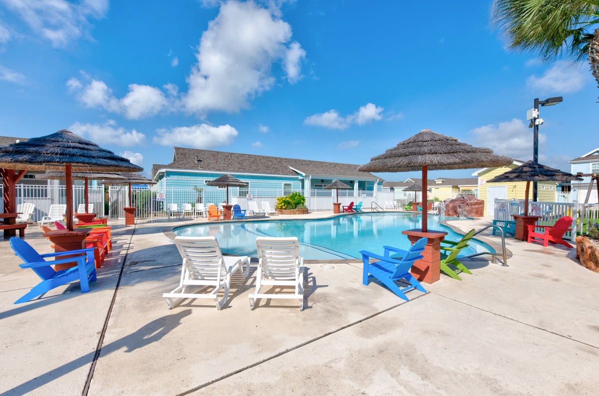 Dive into paradise at your own sparkling pool with colorful lounge chairs and tropical thatched umbrellas under brilliant blue skies.