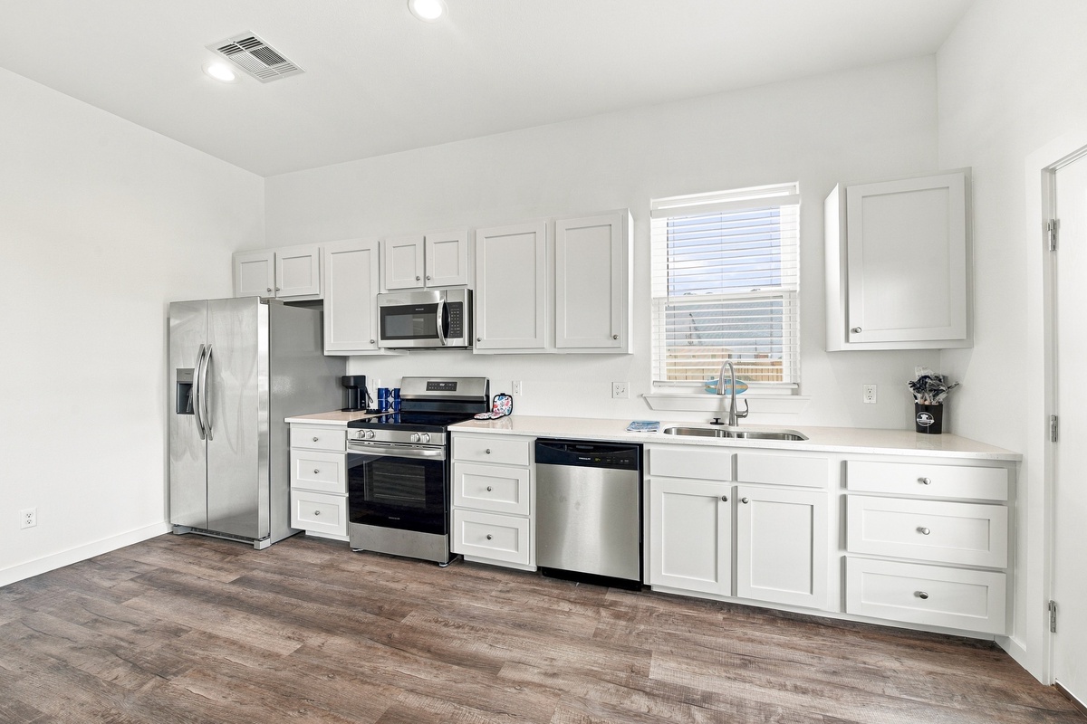 Your modern kitchen features pristine white cabinets, sleek stainless steel appliances, and ample counter space—ready for you to prepare morning coffee or whip up memorable vacation meals.