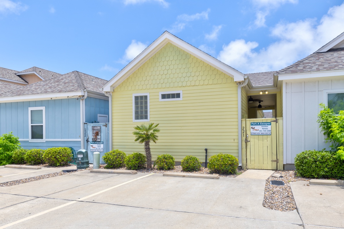 Charming coastal cottages with colorful exteriors and convenient parking create a welcoming beachside retreat.