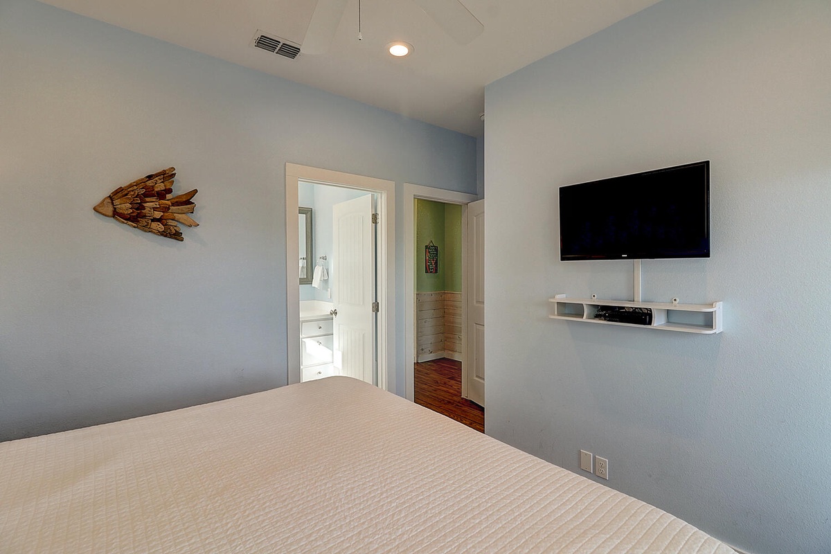 Unwind in your serene bedroom with calming blue walls, a wall-mounted TV for cozy movie nights, and an ensuite bathroom.