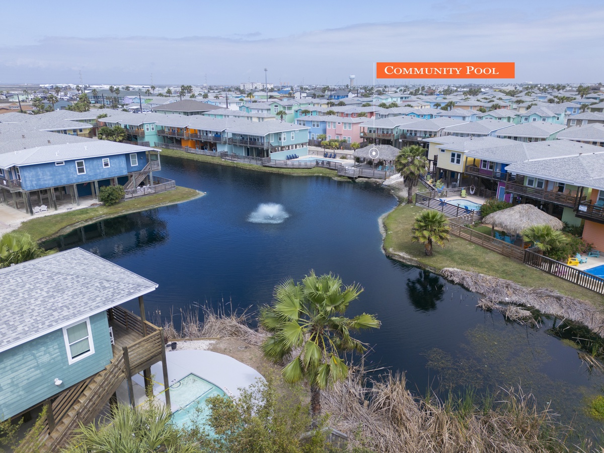 Aerial view of colorful beachside community with scenic lagoon, palm trees, and varied vacation rental homes creating a vibrant coastal neighborhood.
