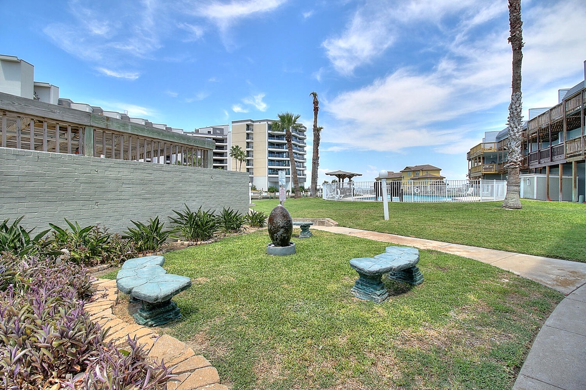 Peaceful garden area with stone benches and walkways, surrounded by landscaped grounds and modern coastal architecture.