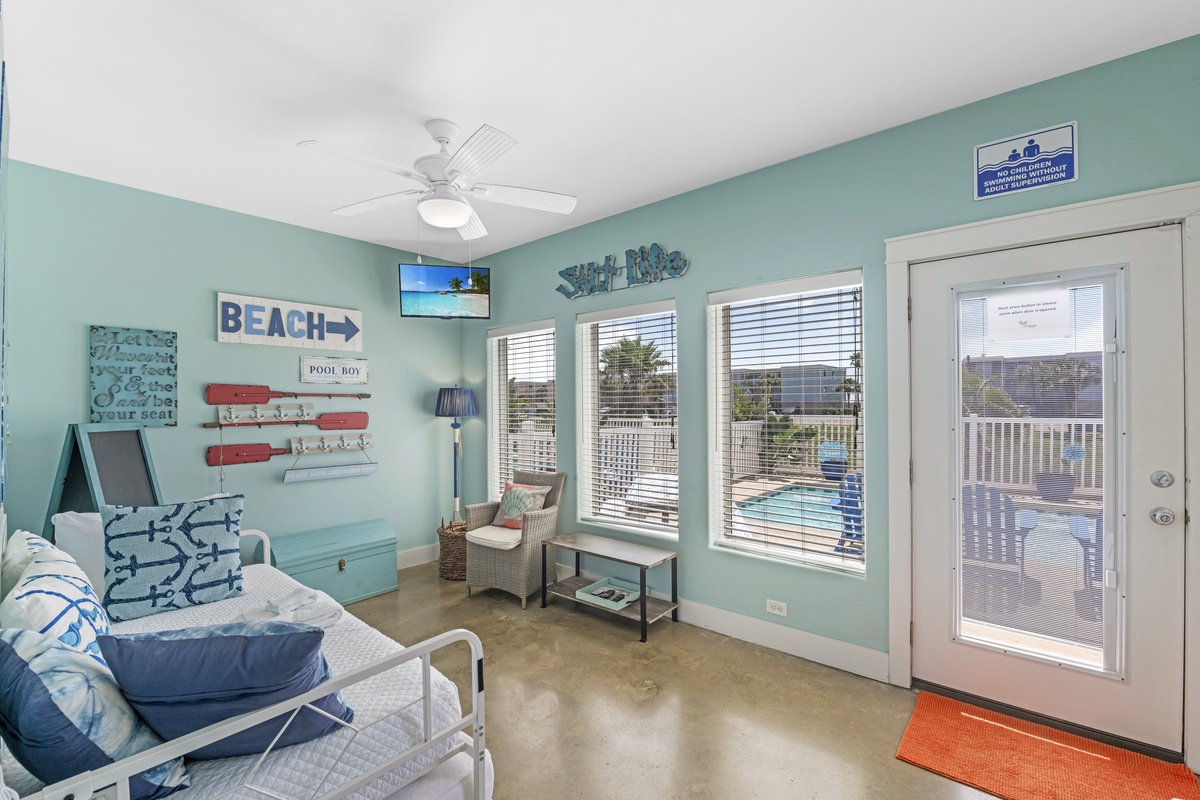 Relax in your beachy living space with coastal decor and pool views through sliding doors.