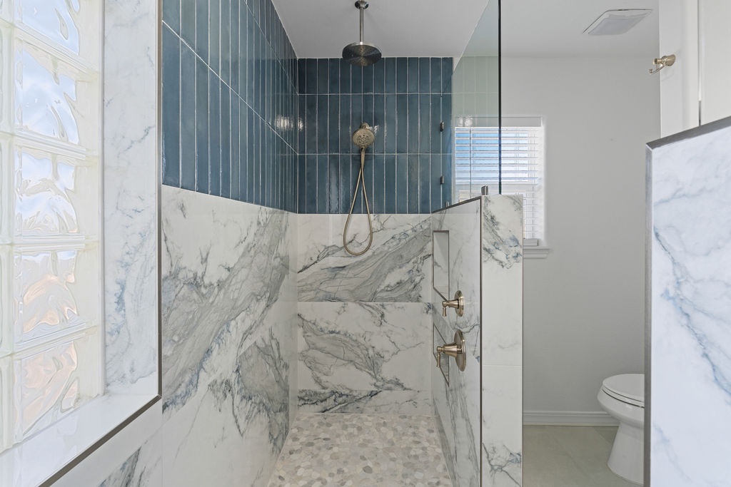 Luxurious marble shower with stunning blue tile accent wall and brass fixtures for your perfect retreat.