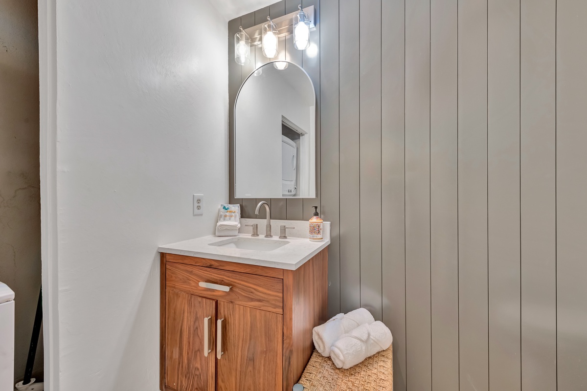 Refresh in your stylish bathroom featuring warm wood vanity, elegant lighting, and soft towels awaiting your arrival.