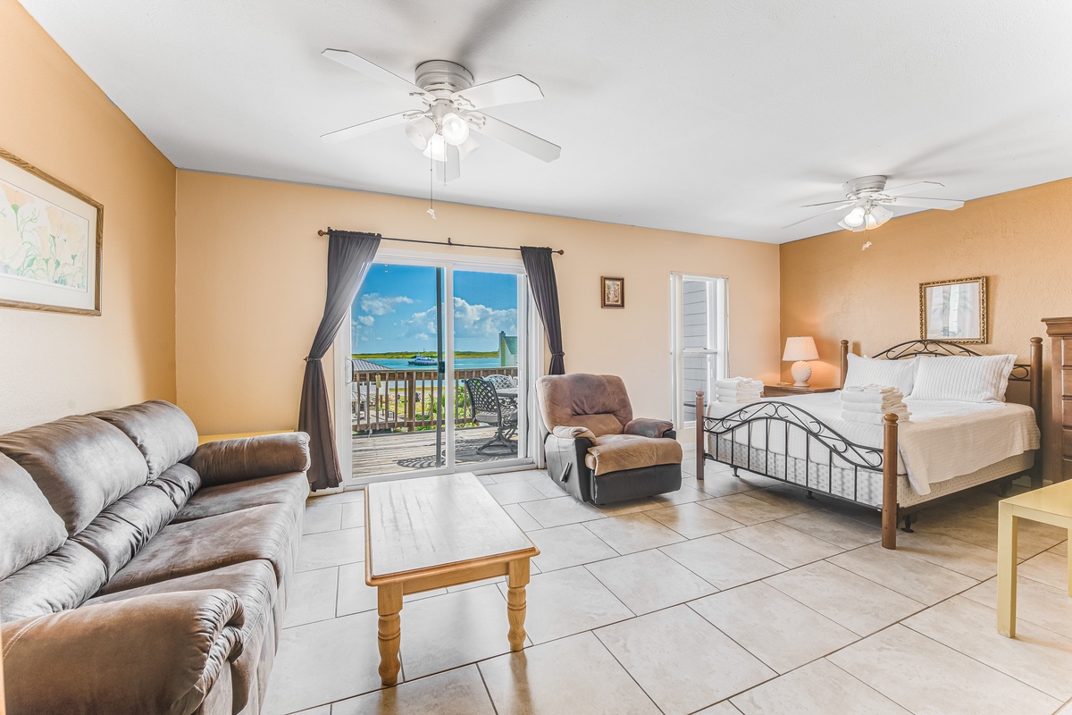 Relax in your spacious suite where comfort meets paradise - plush seating, a cozy bed, and stunning ocean views through your private balcony doors.