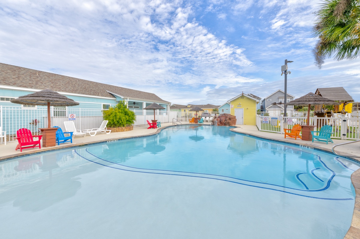 Dive into crystal-clear waters surrounded by colorful Adirondack chairs and tropical palms for your perfect poolside retreat.
