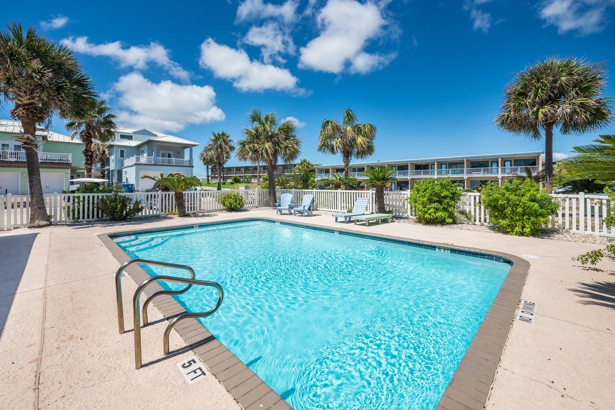 Dive into crystal-clear waters surrounded by swaying palms and tropical landscaping. Your perfect poolside retreat awaits under endless blue skies.