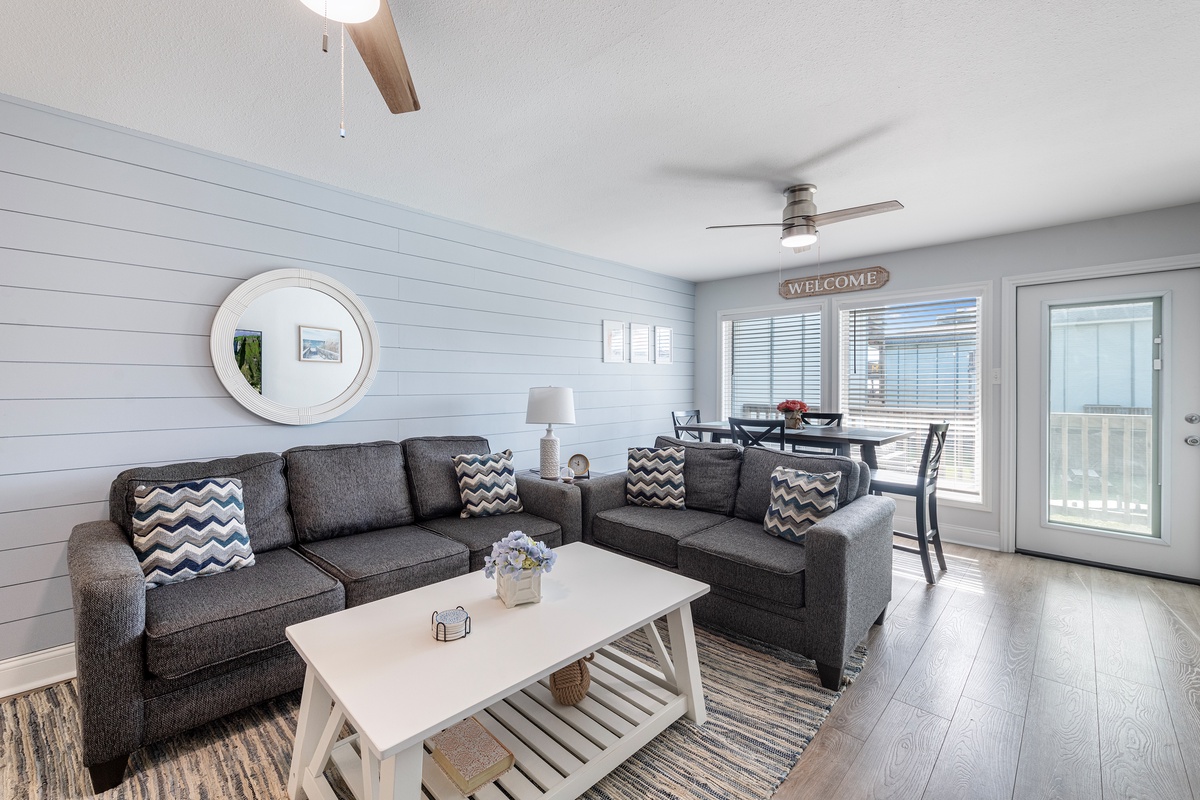 Step into your bright coastal living room with comfy sectional seating, modern decor, and windows that flood the space with natural light.