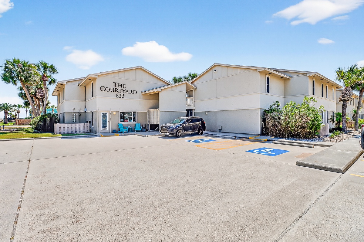 The Courtyard 622 welcomes guests with convenient parking and accessible spaces surrounded by tropical landscaping under sunny skies.
