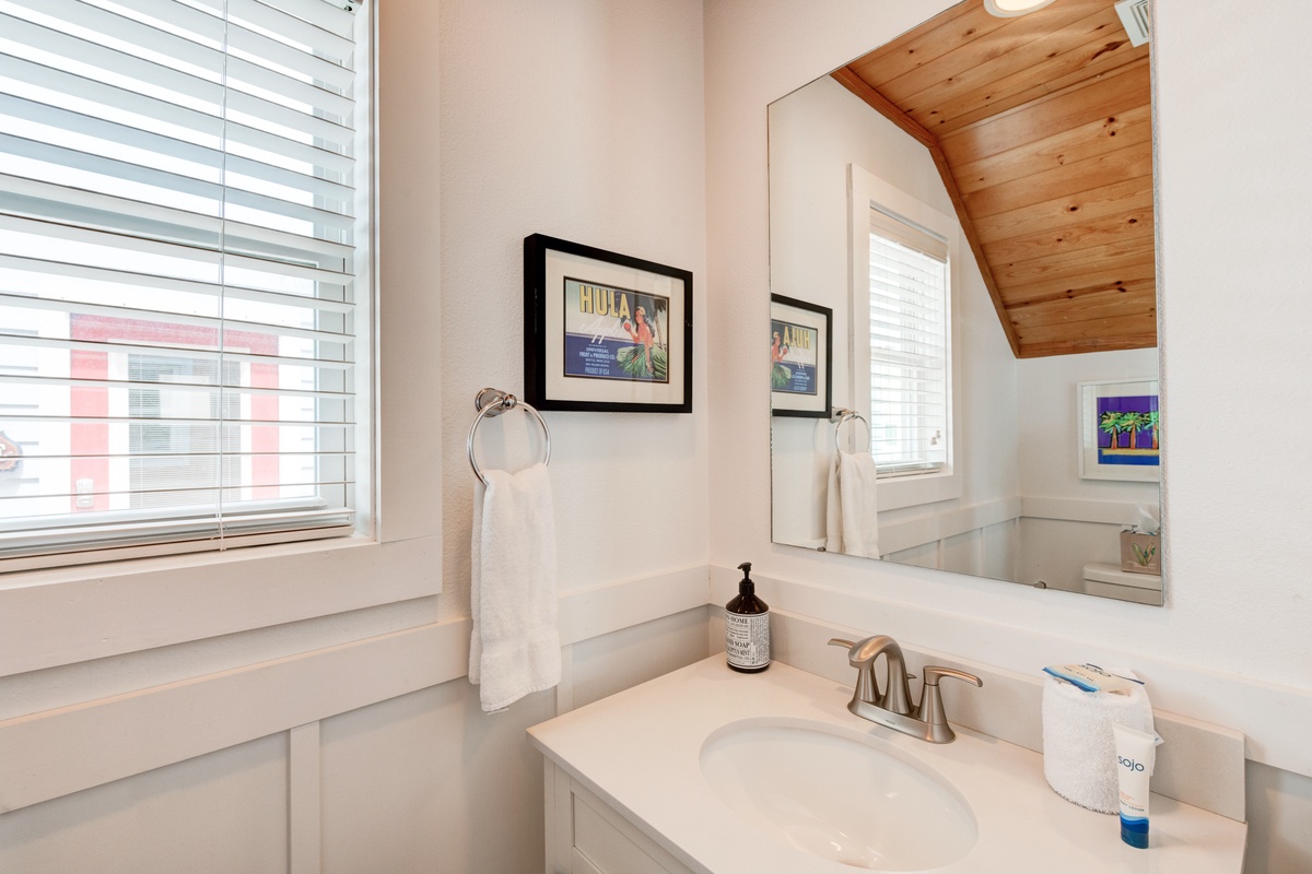 Refresh in your bright, thoughtfully appointed bathroom featuring charming vintage artwork and modern conveniences for your comfort.