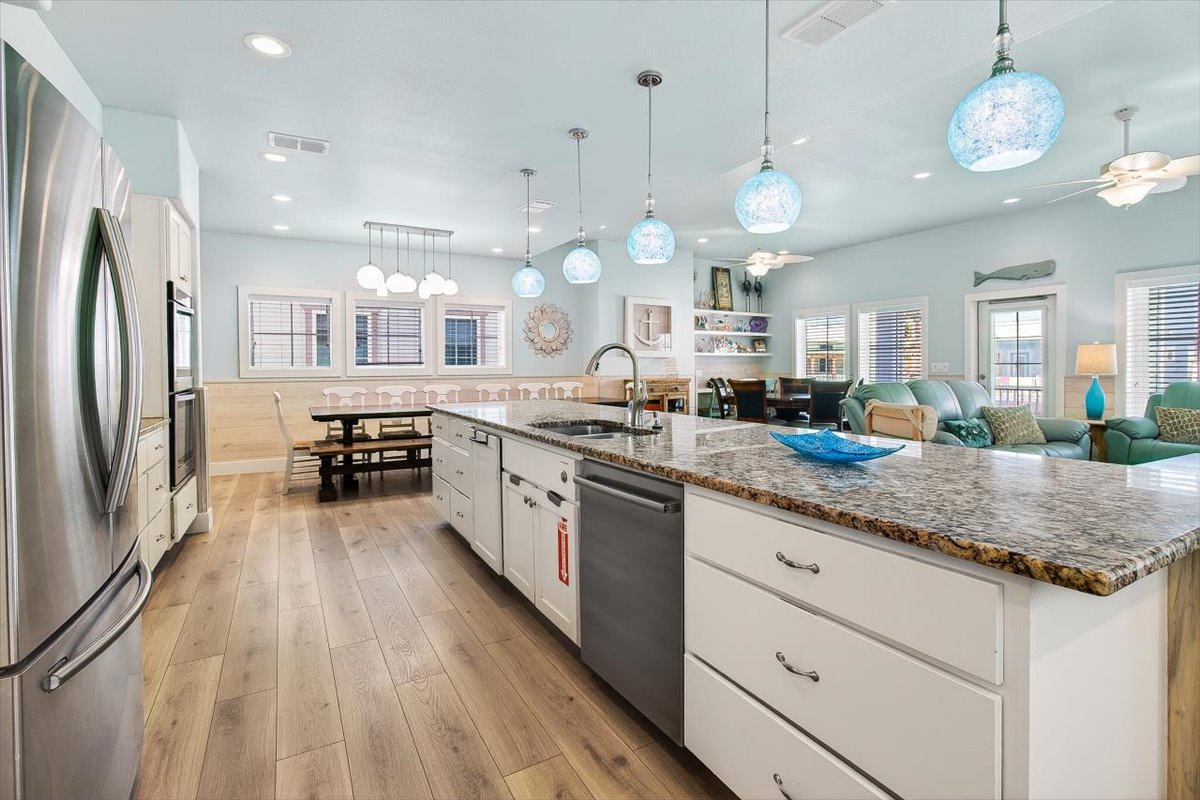 Your gourmet kitchen flows seamlessly into the living area, featuring granite counters, stainless appliances, and stunning coastal-inspired pendant lights.