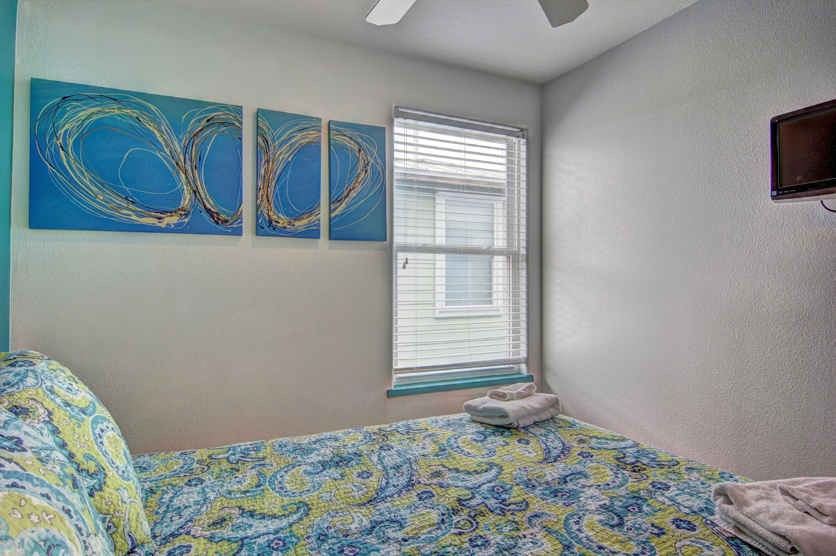 Rest peacefully in your bright bedroom, where vibrant artwork and soft linens create a soothing retreat for rejuvenating sleep.