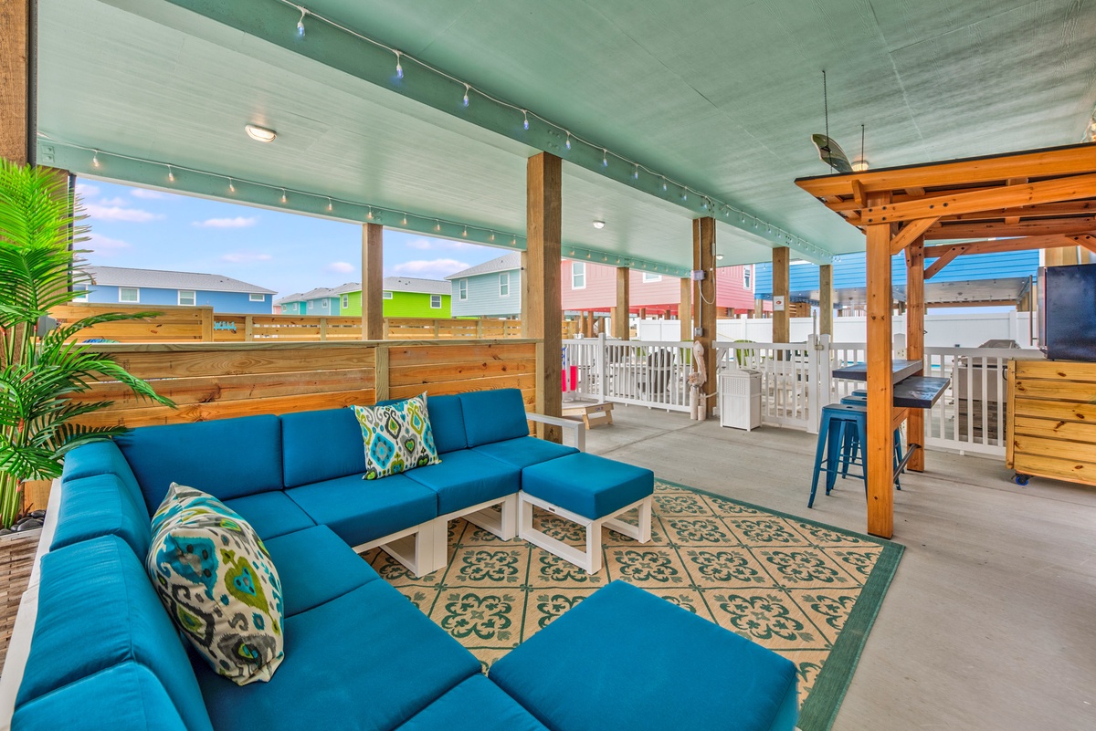 Sink into your private covered patio, where vibrant blue seating and twinkling string lights create the perfect spot for evening conversations.