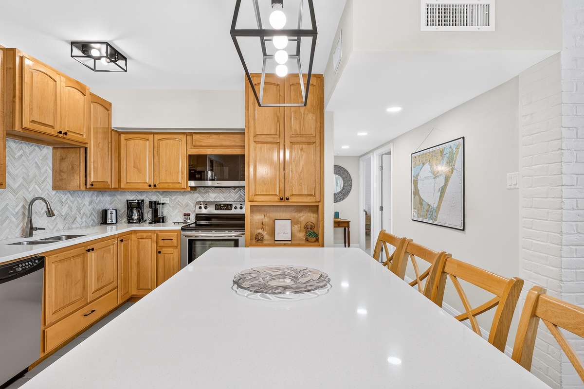 You'll love gathering around this bright kitchen island, where warm wood cabinetry and modern fixtures create the perfect setting for your morning coffee or casual meals together.