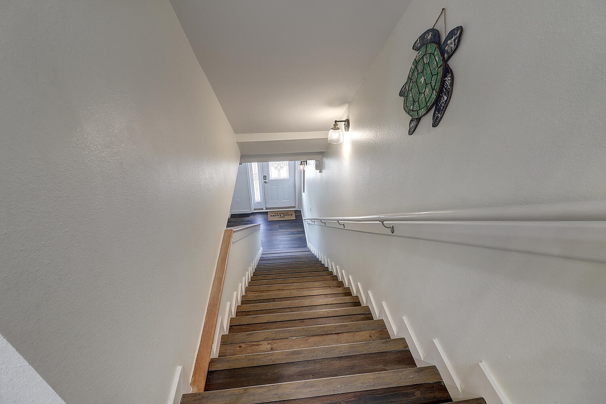 Charming wooden staircase leads you up to your coastal retreat, complete with sea turtle art welcoming you home.