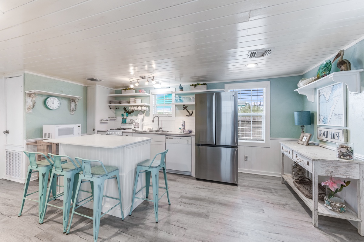 Your spacious kitchen features coastal charm with turquoise accents, modern appliances, and a welcoming breakfast bar perfect for morning coffee.