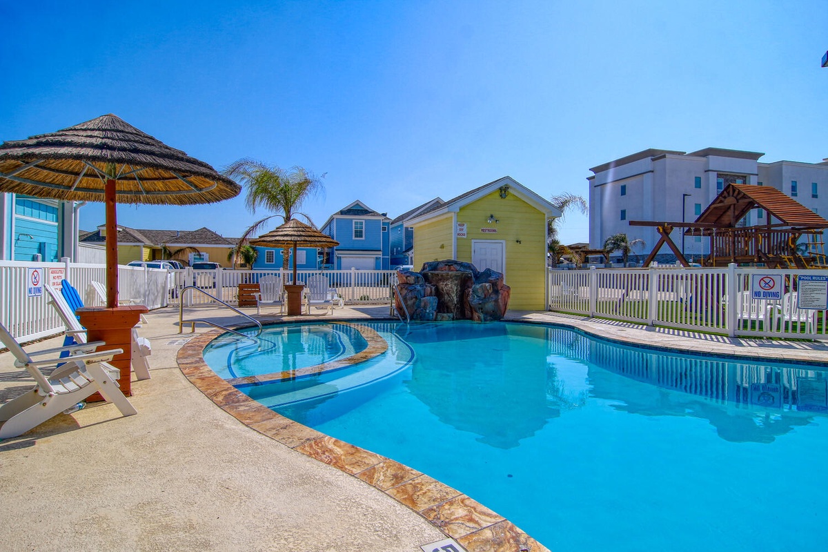 Sparkling pool area with tropical umbrellas and colorful beach cottages creating a vibrant coastal retreat.